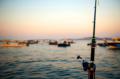 Fishing rod and fishing boats on sunset