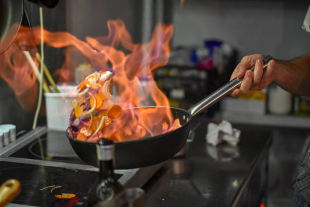 istock Chef tossing vegetables flambe in a pan over the burner 1070898920