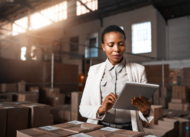 Ensuring all factory operations are running as they should be Shot of a factory manager using a digital tablet in a warehouse huge black woman pictures stock pictures, royalty-free photos & images