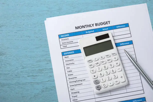 Monthly budget concept with white calculator on blue wood desk background