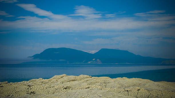 Column basalts formation of Stolbchaty cape at Kunashir, kuril islands, Russia, and Hokkaido island on background, Japan Column basalts formation of Stolbchaty cape at Kunashir at kuril islands, Russia,, and Hokkaido island on background, Japan kunashir island stock pictures, royalty-free photos & images