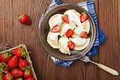 Delicious dumplings with fresh strawberries served with whipped cream and sugar.