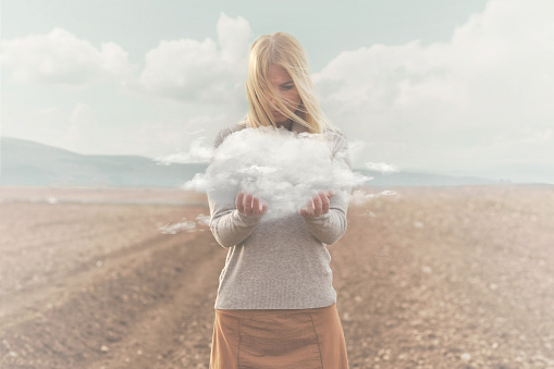 momento surrealista, mujer sosteniendo en sus manos una nube suave photo