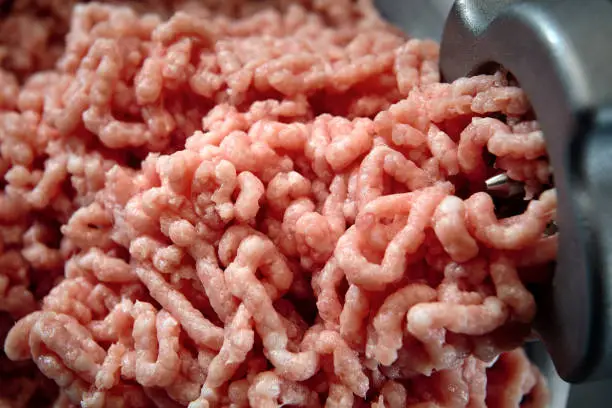 Minced meat coming out from grinder close-up. Healthy fresh homemade minced meat texture. Place for copyspace.
