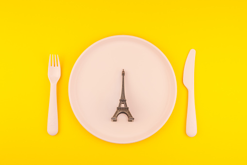 Small Eiffel tower love symbol plate serving plastic tableware copy space on bold yellow background in creative minimal style. Concept Valentine love holiday travel feminine blog social media