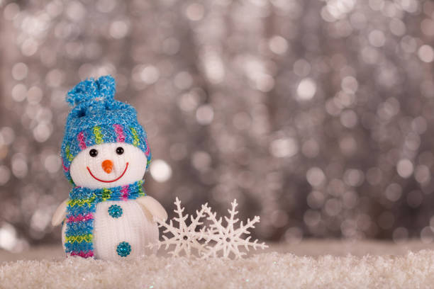 istock Smiling snowman and snowflakes on gray background with bokeh effect 1070942896