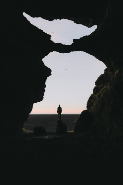 istock Man standing on the rock in cave in Iceland 1070949360