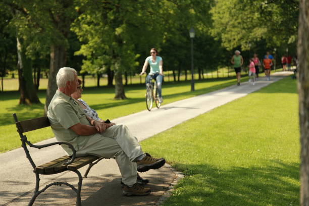 A senior couple sits on a bench at a retirement community.  They look out into the distance together.