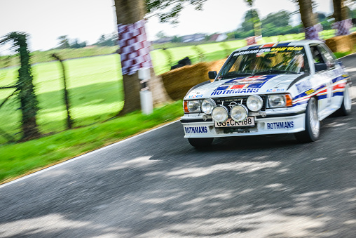 Opel Ascona B400 1980s rally car driving fast on a country road. The car is doing a demonstration drive during the 2017 Classic Days event at Schloss Dyck.