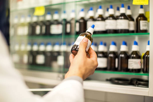 pharmacien, tenant une bouteille de médecine dans la main - homeopatic medicine photos et images de collection