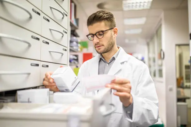 Pharmacist checking medicines on rack. Chemist searching the medicines at storage self.