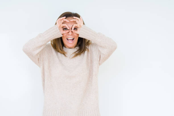 istock Beautiful middle age woman over isolated background doing ok gesture like binoculars sticking tongue out, eyes looking through fingers. Crazy expression. 1070963036