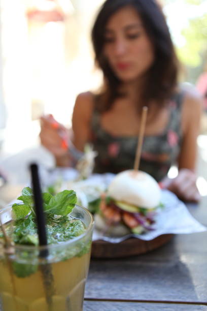istock Young woman eating a hamburger in a restaurant openair 1070963548