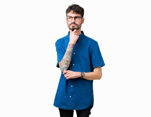 istock Young handsome man wearing glasses over isolated background with hand on chin thinking about question, pensive expression. Smiling with thoughtful face. Doubt concept. 1070964986
