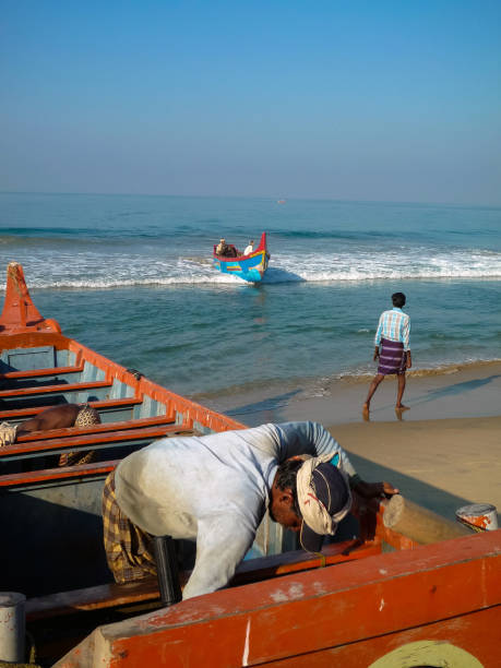 India, Kerala, Varkala, 02/01/2009: a traditional fishing boat lands on the shore of Varkala beach