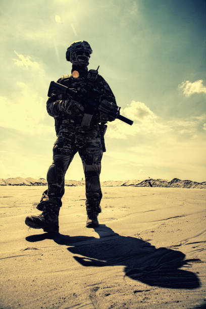 istock Equipped army soldier with rifle walks in desert 1070971302