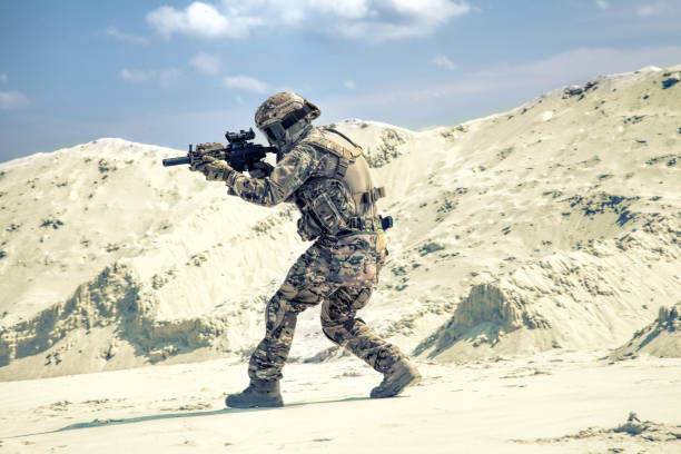 istock Man in military uniform playing airsoft in sands 1070971420