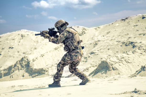 чел�овек в военной форме играет в страйкбол в песках - airsoft стоковые фото и изображения