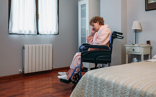 Senior woman in a wheelchair alone in a room