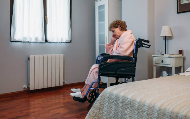 Senior woman in a wheelchair alone Senior woman in a wheelchair alone in a room hospital depression sadness bed stock pictures, royalty-free photos & images