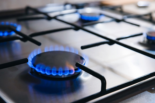 Kitchen stove with blue flames burning. Blue flames from gas stove burner.