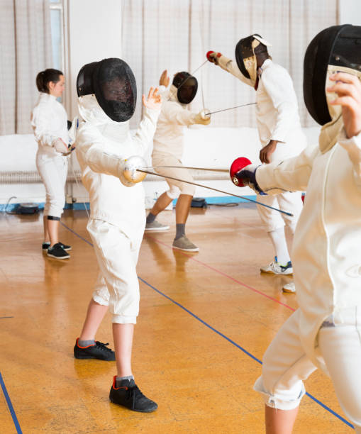 istock Adults and teens wearing fencing uniform practicing with foil 1070983852