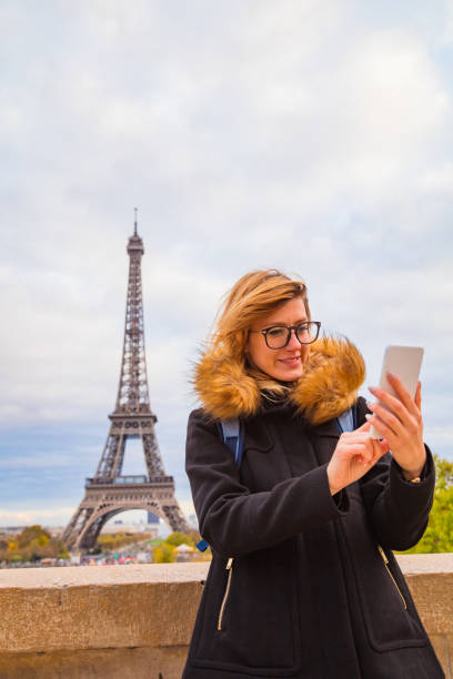 istock Girl using cellphone with Paris city background and Eiffel tower. 1070990934