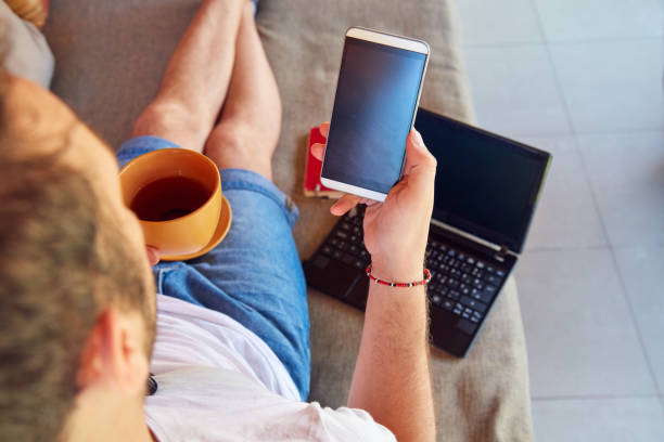 istock Man using cellphone and laptop while drinking coffee / tea on the porch. 1070995494