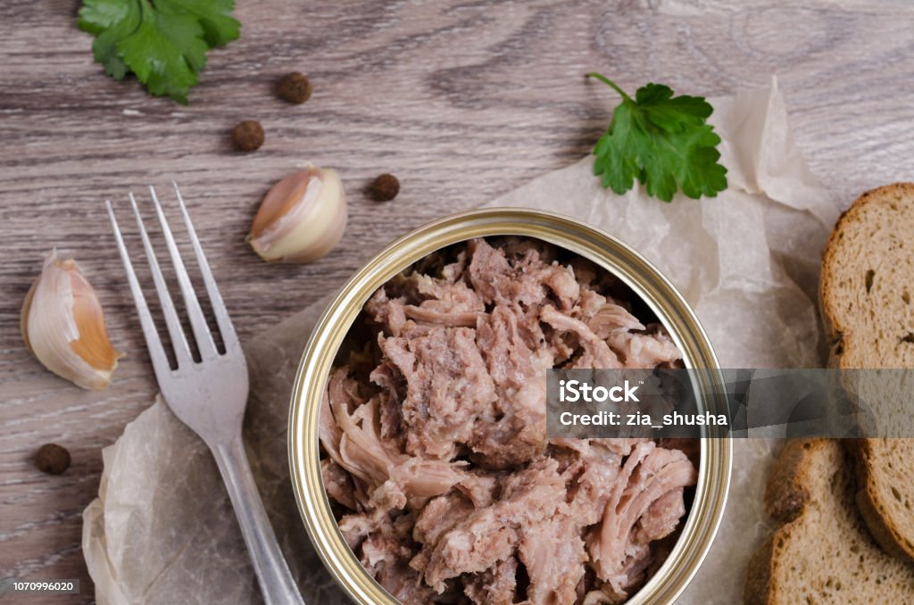 Canned meat fillet Canned meat fillet in a metal can on a wooden background. Selective focus. Can Stock Photo