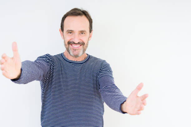 istock Handsome senior man over isolated background looking at the camera smiling with open arms for hug. Cheerful expression embracing happiness. 1070999164