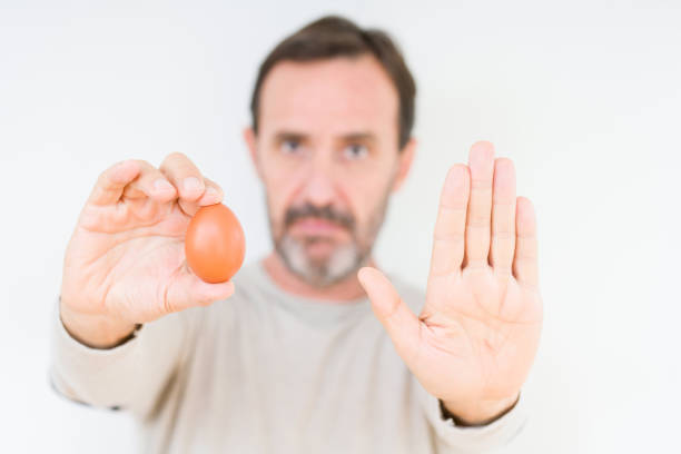 istock Senior man holding fresh egg over isolated background with open hand doing stop sign with serious and confident expression, defense gesture 1070999356