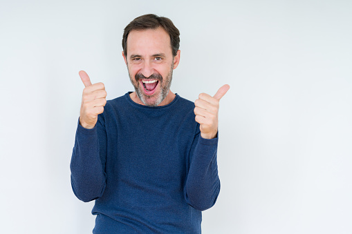 Elegant senior man over isolated background success sign doing positive gesture with hand, thumbs up smiling and happy. Looking at the camera with cheerful expression, winner gesture.