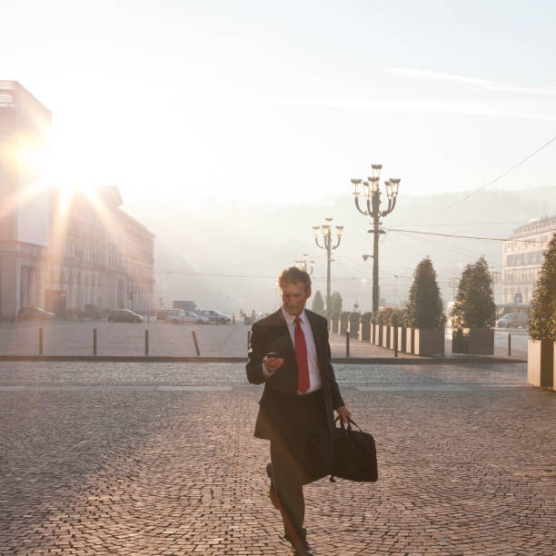 istock Businessman uses cell phone while walking in piazza 1070999830