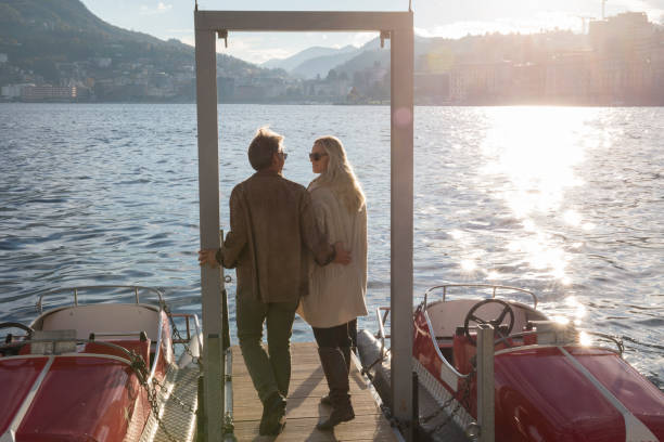 istock Couple walk down dock on lake with sun and mountains 1071000306