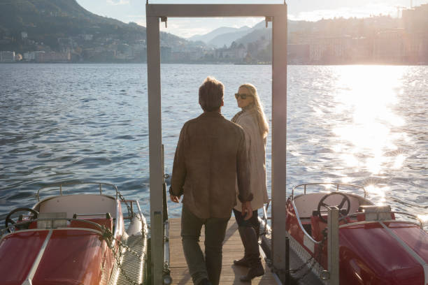 istock Couple walk down dock on lake with sun and mountains 1071000412