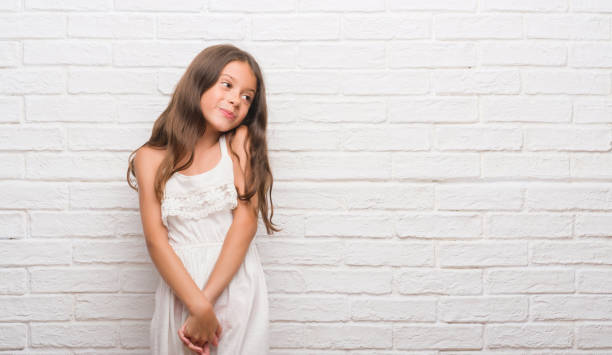istock Young hispanic kid over white brick wall looking away to side with smile on face, natural expression. Laughing confident. 1071002164
