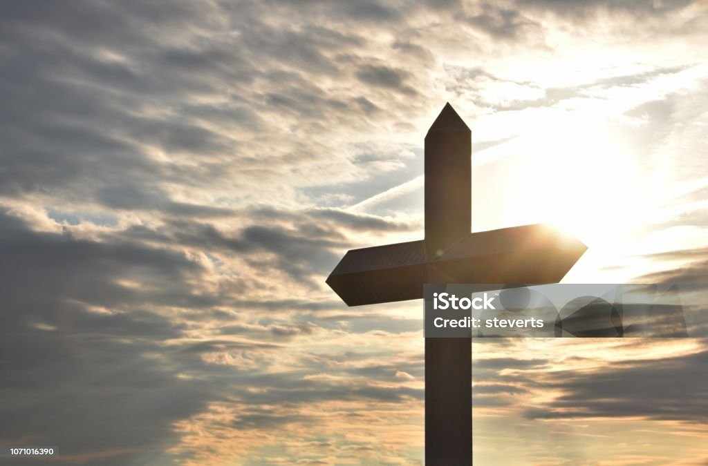 Cross at Sunrise Structural Christian cross with sun rising behind it. Blue Stock Photo