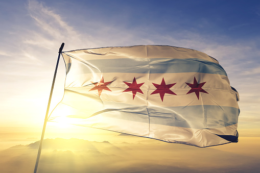 Chicago city of United States flag on flagpole textile cloth fabric waving on the top sunrise mist fog