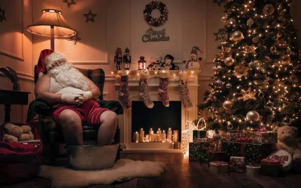 Funny Santa Claus relaxing after or before work in cozy christmas room