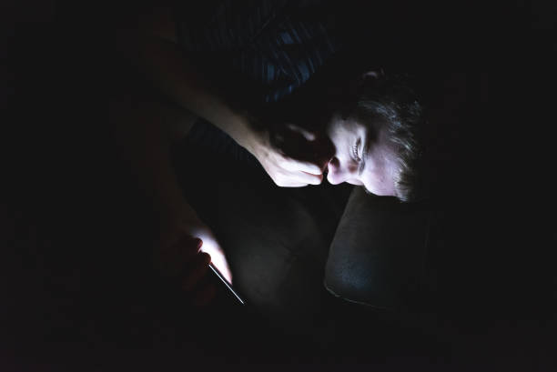 istock Curious teenager scrolling through his cellphone in the dark. 1071024830