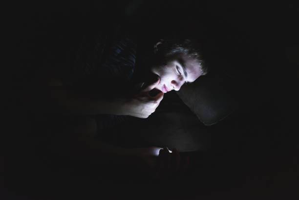 istock Curious teenager scrolling through his cellphone in the dark. 1071024906