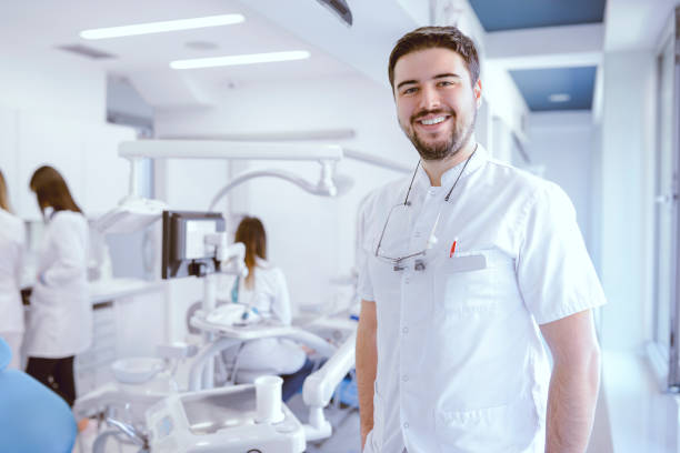 istock Handsome Young Dentist Posing In Clinic While His Colleagues Working 1071025096