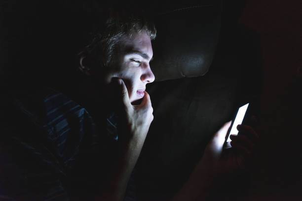 istock Curious teenager scrolling through his cellphone in the dark. 1071025596