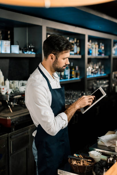 istock Barman standing in apron with digital tablet in bar 1071027228