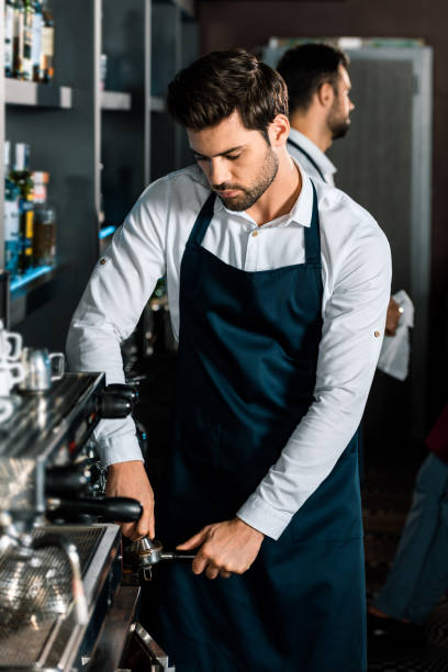 istock handsome barista in apron using coffee machine at workplace 1071027326