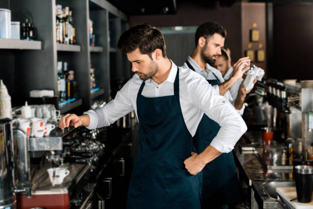 istock adult handsome barista in apron making coffee at workplace 1071027334