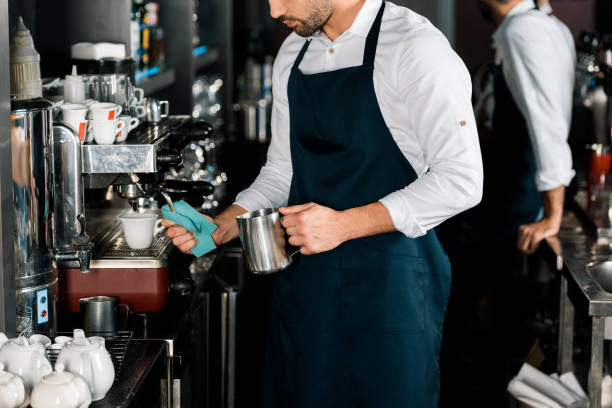 istock cropped view of barman in apron preparing coffee with coffee machine 1071027372