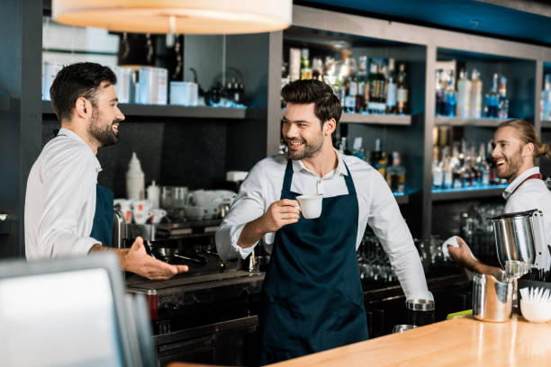 istock handsome cheerful barman drinking coffee and speaking with colleagues at workplace 1071027376
