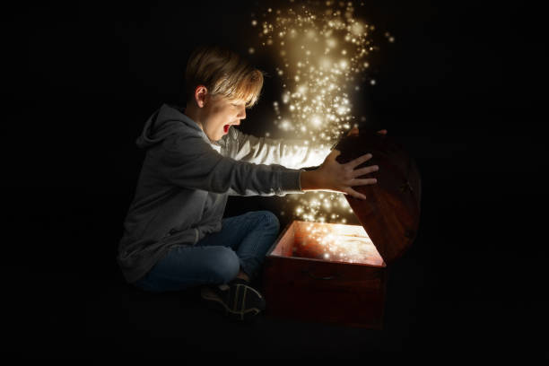 little blond boy opens a chest little blond boy opens a chest anxiously, light inside, glitter bright little boys blue eyes blond hair one person stock pictures, royalty-free photos & images