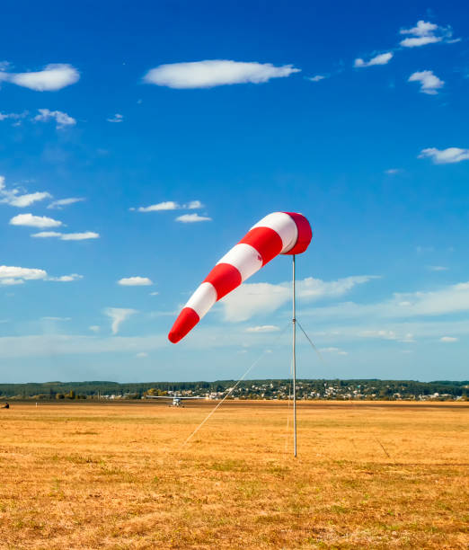 istock red and white windsock wind sock on blue sky on the aerodrome, yellow field and clouds background in autumn 1071032802